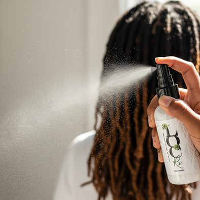 Person using a hair care product on their hair with a neutral background